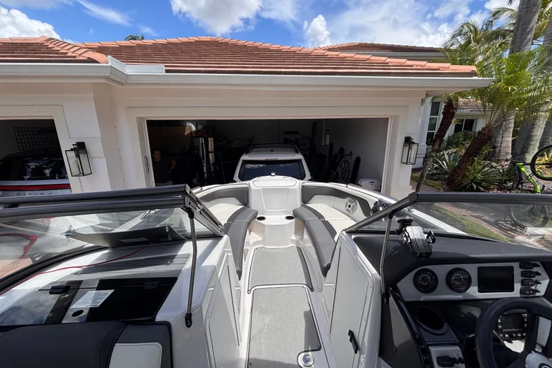Slide: The Image of 2022 Yamaha AR210 boat parked in front of a garage under a clear blue sky. - 28