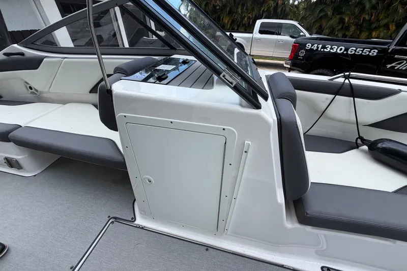 Slide: The Image of 2022 Yamaha Boats AR210 interior with gray seating and storage compartment. - 28