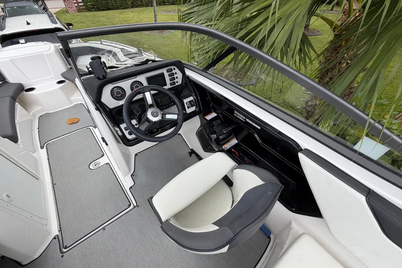 Slide: The Image of 2022 Yamaha Boats AR210 cockpit with steering wheel, dashboard, and seating, surrounded by greenery. - 17