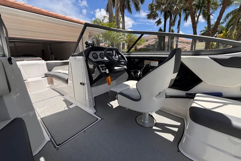 Slide: The Image of 2022 Yamaha AR210 boat interior with steering wheel and seating under sunny skies. - 34