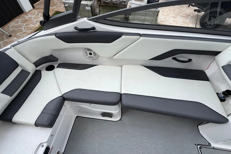 Slide: The Image of 2022 Yamaha Boats AR210 interior seating with white and gray upholstery. - 11
