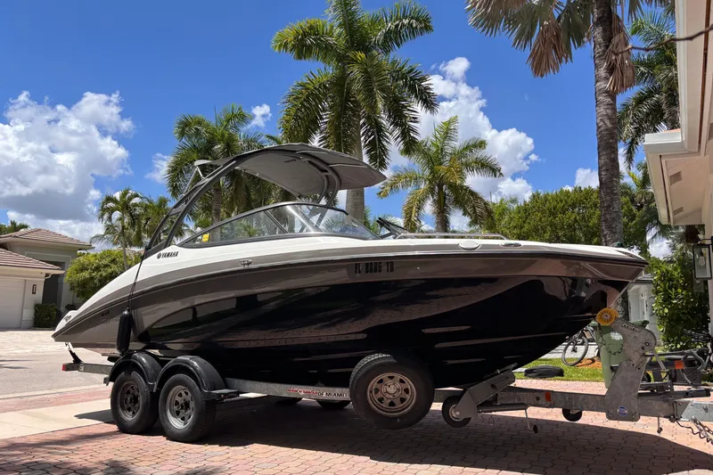 Slide: The Image of 2022 Yamaha Boats AR210 on trailer, parked in tropical driveway with palm trees. - 6