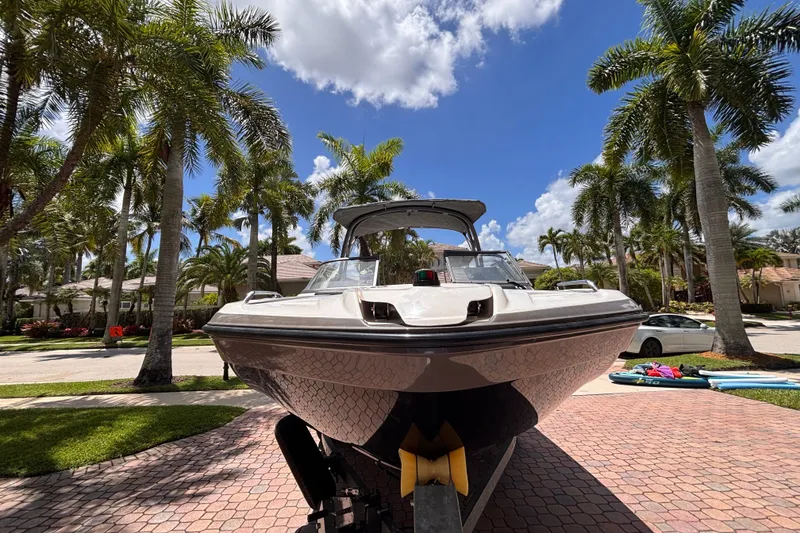 Slide: The Image of 2022 Yamaha Boats AR210 on trailer, surrounded by palm trees under a clear blue sky. - 4