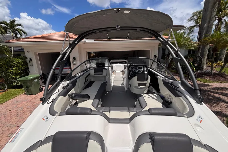 Slide: The Image of 2022 Yamaha Boats AR210 interior view, showcasing seating and steering, parked in a driveway. - 20