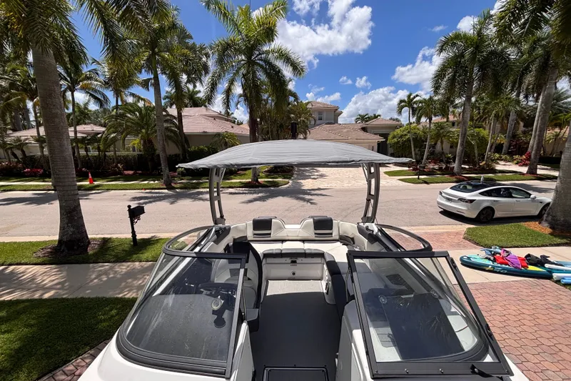 Slide: The Image of 2022 Yamaha Boats AR210 parked in a sunny, palm-lined residential area. - 39