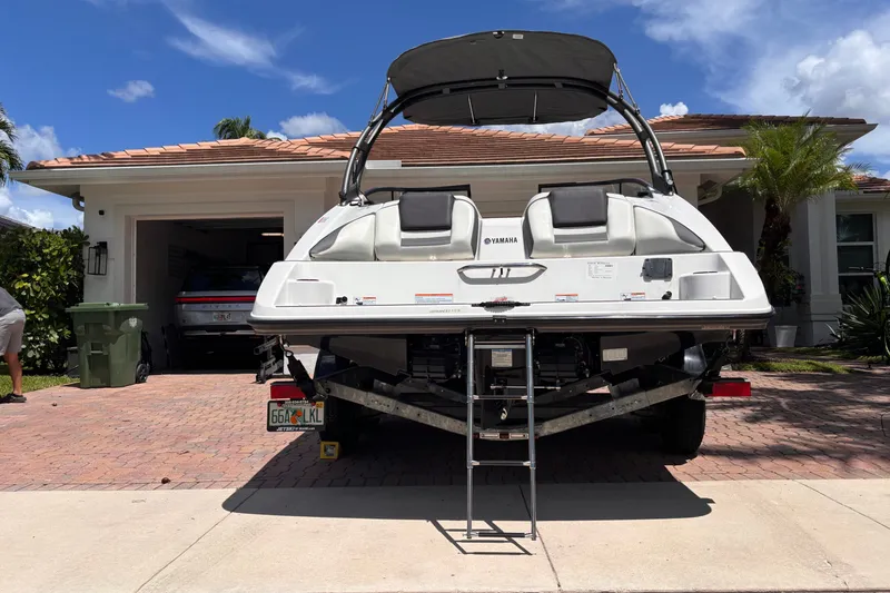 Slide: The Image of 2022 Yamaha AR210 boat parked in a driveway, showcasing rear view and ladder. - 17