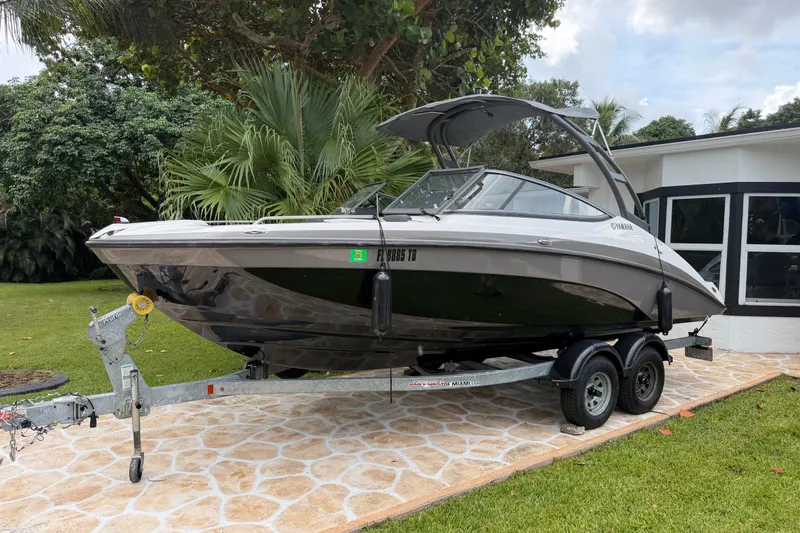 Slide: The Image of 2022 Yamaha AR210 boat on trailer, parked in a lush garden setting. - 4