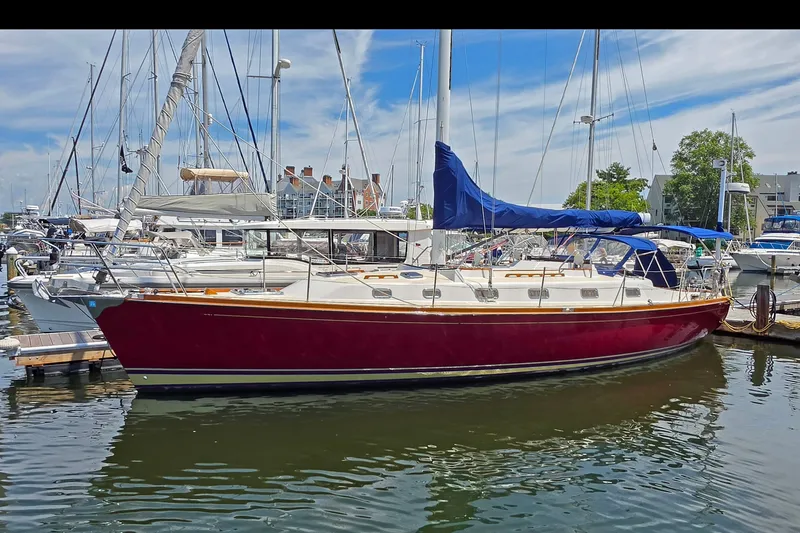 The Image of 2008 Tartan 4300 sailboat docked in marina, featuring red hull and blue sail cover. - 0