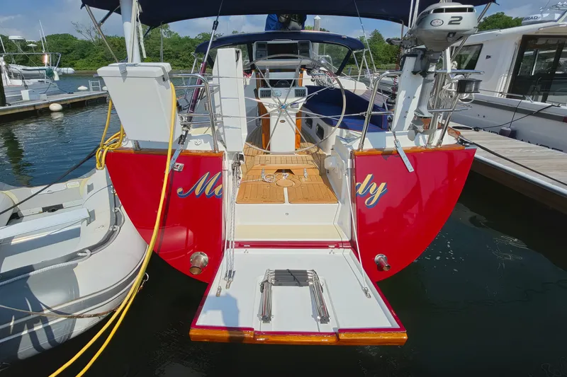 Slide: The Image of Red Tartan 4300 sailboat from 2008 docked at a marina, featuring a wooden deck. - 4