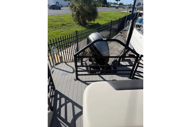 Slide: The Image of 2023 SunChaser Geneva Sport 23 SB boat with outboard motor and railing, parked near a road. - 15