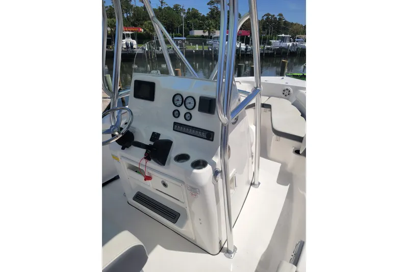 Slide: The Image of 2020 Tidewater 198 CC Adventure boat console with steering wheel and gauges, docked by the water. - 3