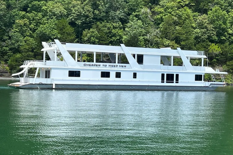 Slide: The Image of 1999 Stardust Cruisers 20 x 123 houseboat on a serene lake with lush green backdrop. - 4