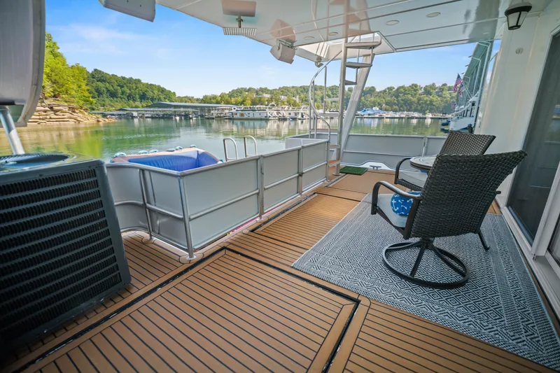 Slide: The Image of 1999 Stardust Cruisers 20 x 123 houseboat deck with seating, overlooking serene lake and marina. - 38