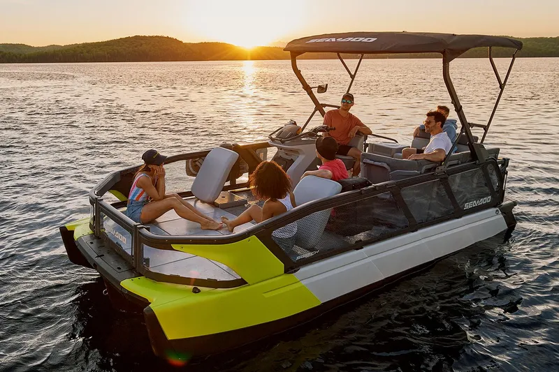 Slide: The Image of Manufacturer Provided Image: 2023 Sea-Doo Switch Sport 21 pontoon boat on a lake at sunset with passengers. - 21