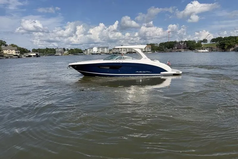 Slide: The Image of 2019 Regal 3300 Bowrider cruising on a scenic lake under a partly cloudy sky. - 2