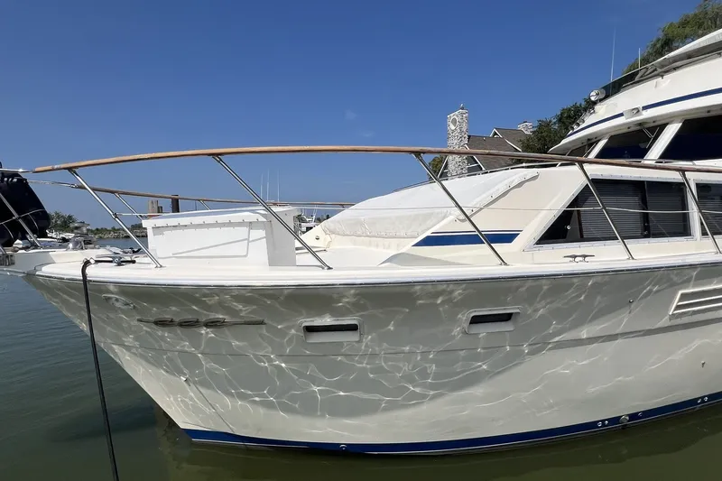 Slide: The Image of 1986 Chris Craft 47 Constellation yacht docked, reflecting sunlight on calm water. - 9