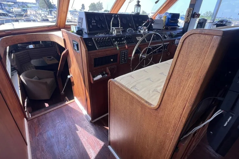 Slide: The Image of 1986 Chris Craft 47 Constellation yacht interior with wooden helm and seating area. - 23