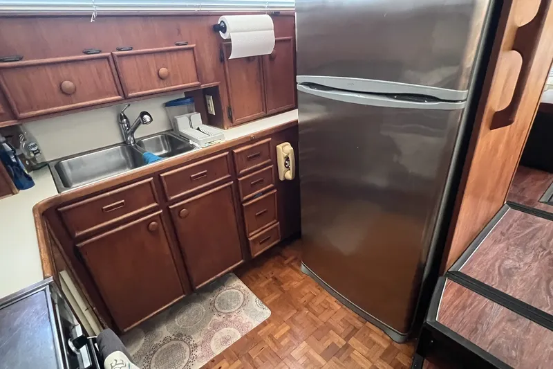 Slide: The Image of Kitchen area of 1986 Chris Craft 47 Constellation with wooden cabinets and stainless steel fridge. - 30