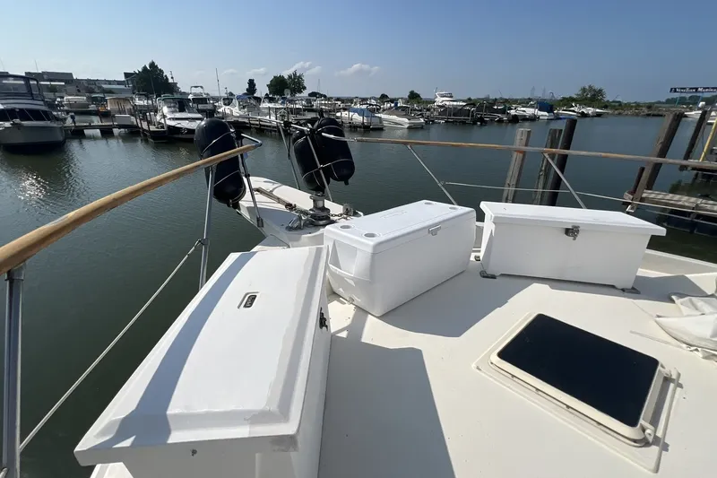 Slide: The Image of 1986 Chris Craft 47 Constellation yacht docked at marina, featuring deck storage boxes. - 115