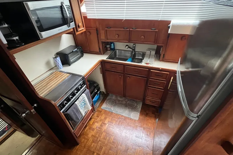 Slide: The Image of 1986 Chris-Craft 46 Constellation yacht kitchen with wooden cabinets, stove, and modern appliances. - 88