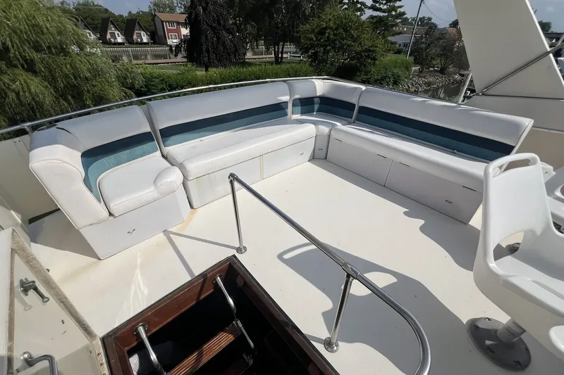 Slide: The Image of 1986 Chris Craft 47 Constellation yacht deck with white seating and scenic background. - 85