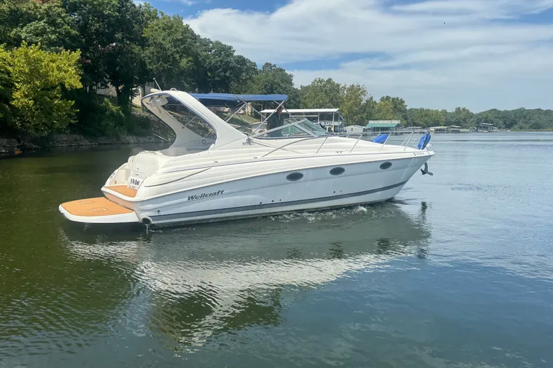 Slide: The Image of 2000 Wellcraft 3300 Martinique boat cruising on a calm lake under a clear sky. - 2
