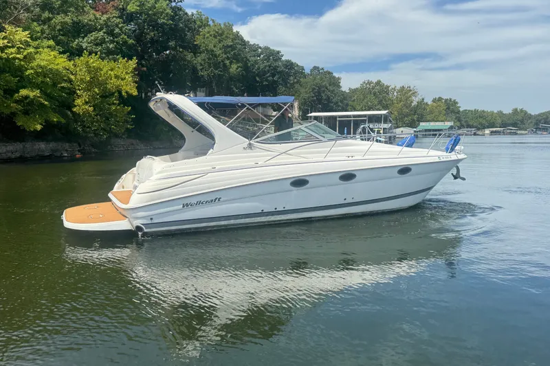 Slide: The Image of 2000 Wellcraft 3300 Martinique boat on calm water, surrounded by lush greenery. - 3