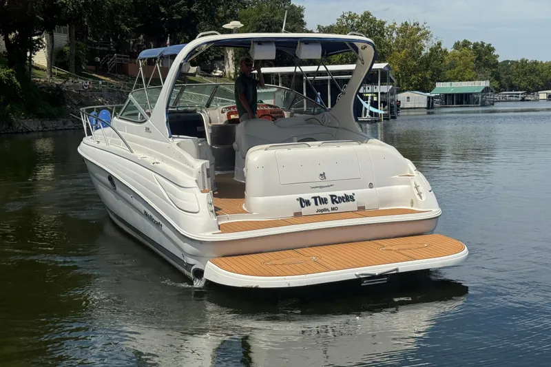 Slide: The Image of 2000 Wellcraft 3300 Martinique boat on calm water, rear view with wooden deck. - 5