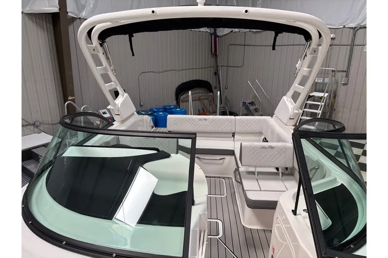 Slide: The Image of 2026 Sea Ray SDX 230 boat interior with seating and windshield in a storage facility. - 13
