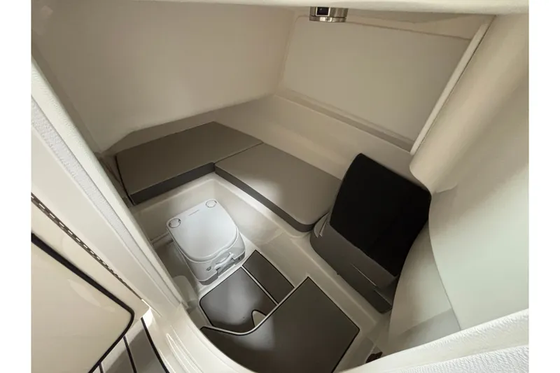 Slide: The Image of 2026 Sea Ray SDX 230 boat interior cabin with compact toilet and seating area. - 14