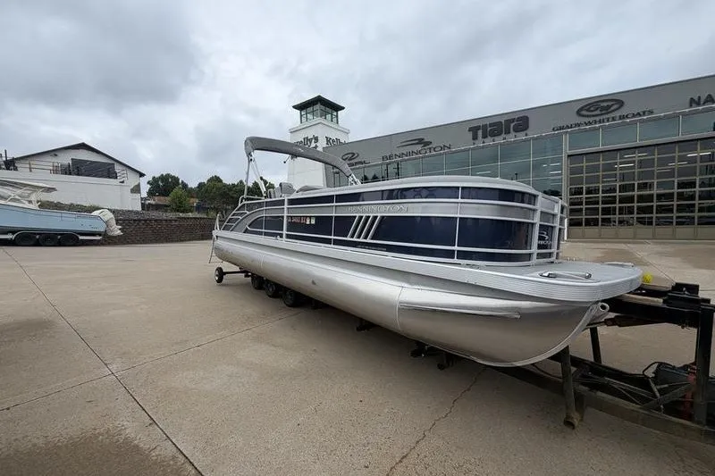 The Image of 2023 Bennington 25 LSB pontoon boat on trailer outside dealership. - 1