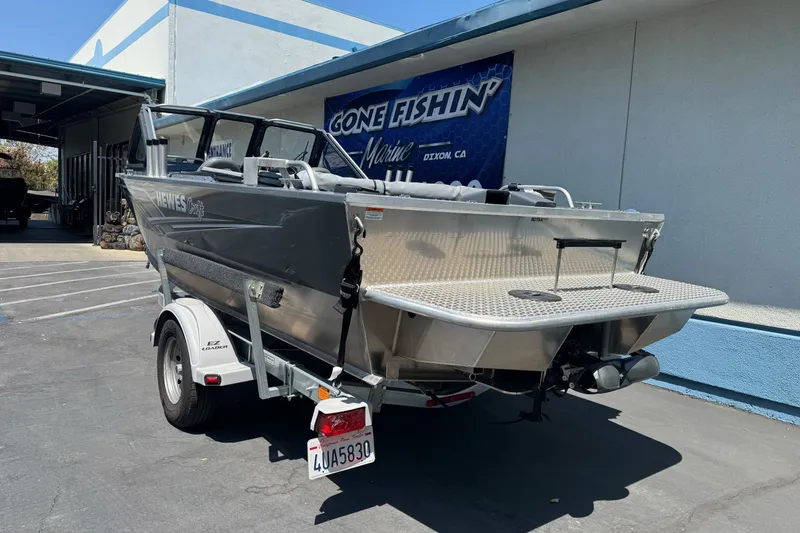 Slide: The Image of 2021 Hewescraft 180 River Runner boat on trailer outside a marine shop. - 7