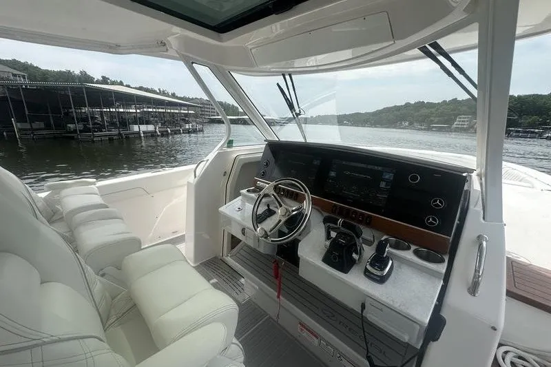 Slide: The Image of Cockpit view of 2021 Regal 38 SAV boat with modern controls and waterfront backdrop. - 27