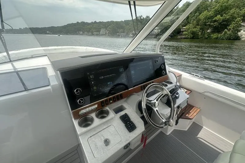 Slide: The Image of Cockpit of 2021 Regal 38 SAV boat with modern controls and scenic lake view. - 16