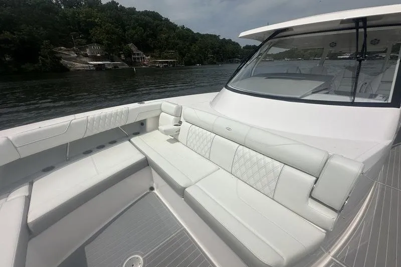 Slide: The Image of 2021 Regal 38 SAV boat with spacious white seating on a calm lake. - 14