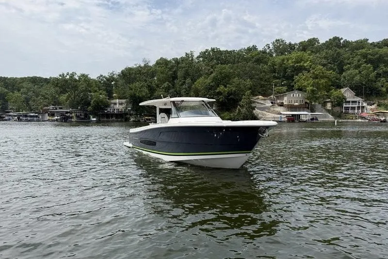 Slide: The Image of 2021 Regal 38 SAV boat on a serene lake with lush green shoreline. - 4