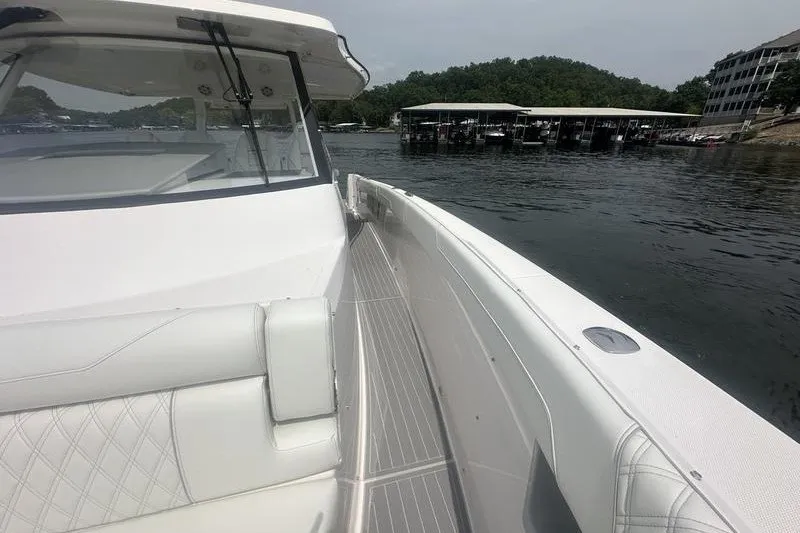 Slide: The Image of 2021 Regal 38 SAV boat on calm water near docks and greenery. - 13