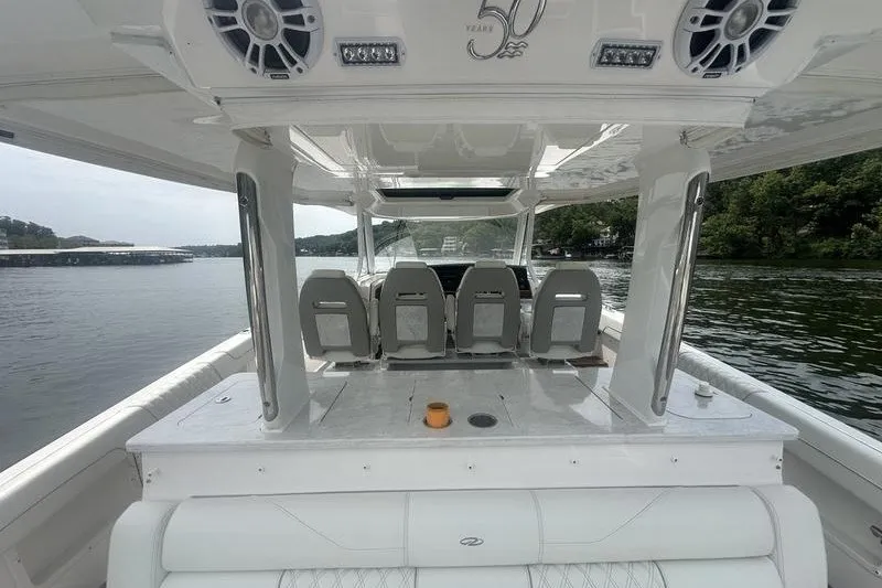 Slide: The Image of 2021 Regal 38 SAV boat interior with seating and speakers on a calm lake. - 24