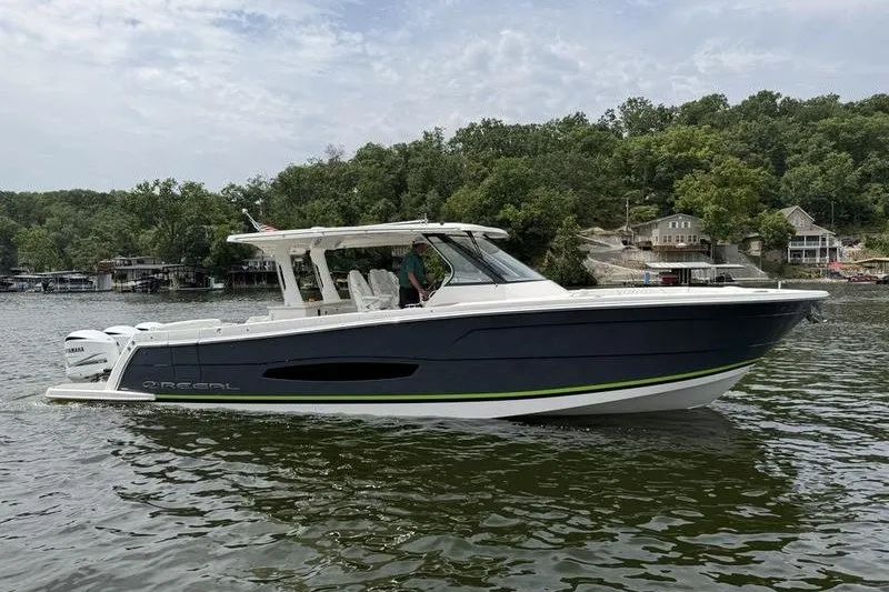 The Image of 2021 Regal 38 SAV boat cruising on a lake with wooded shoreline background. - 1