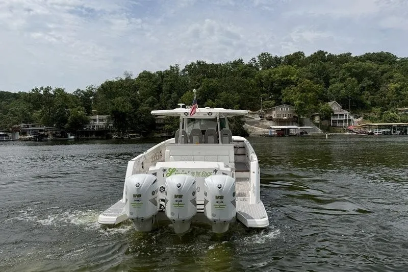 Slide: The Image of 2021 Regal 38 SAV boat with triple outboard engines on a scenic lake. - 9