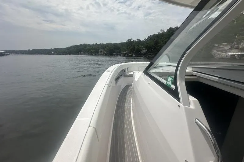 Slide: The Image of 2021 Regal 38 SAV boat cruising on a calm lake under a cloudy sky. - 28