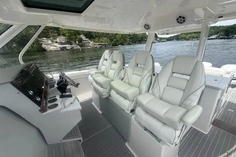 Slide: The Image of 2021 Regal 38 SAV boat interior with luxurious white seating and scenic lake view. - 15