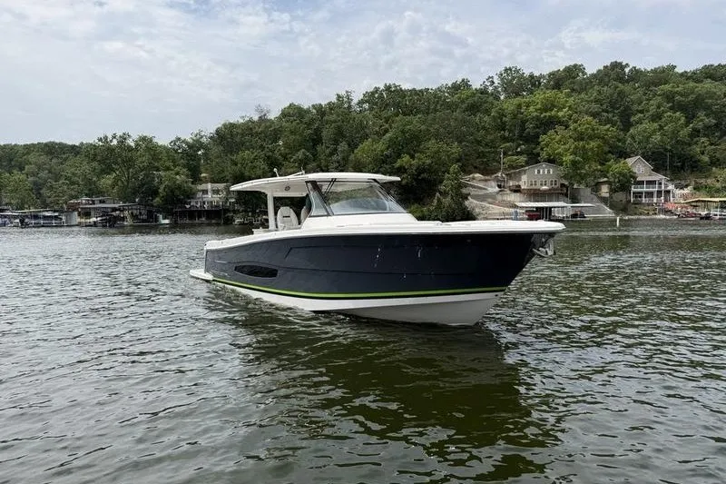 Slide: The Image of 2021 Regal 38 SAV boat on a serene lake with lush green shoreline. - 10