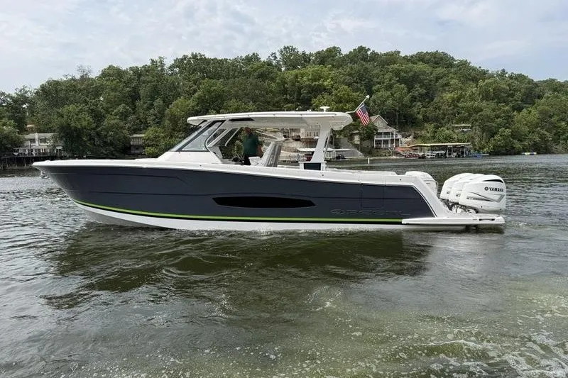 Slide: The Image of 2021 Regal 38 SAV boat cruising on a lake with lush green shoreline. - 6