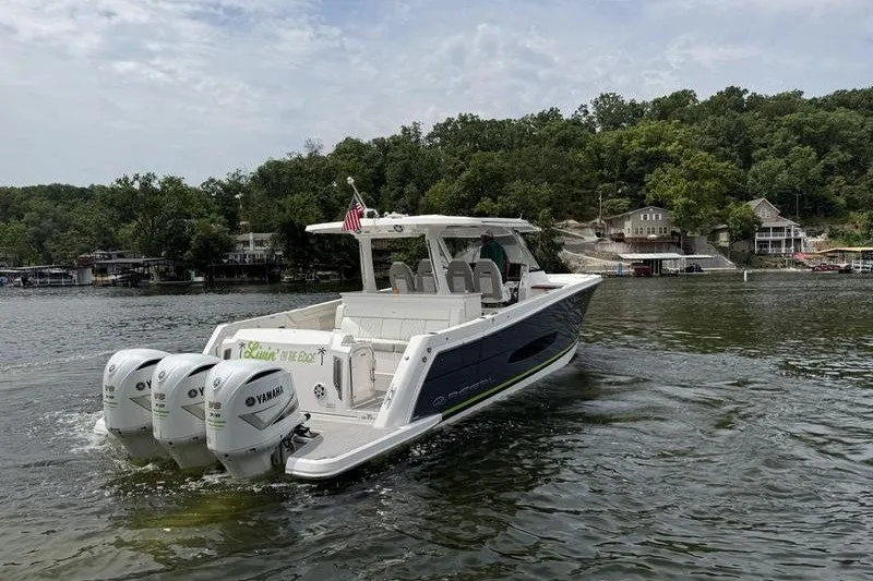 Slide: The Image of 2021 Regal 38 SAV boat with triple Yamaha engines on a scenic lake. - 2