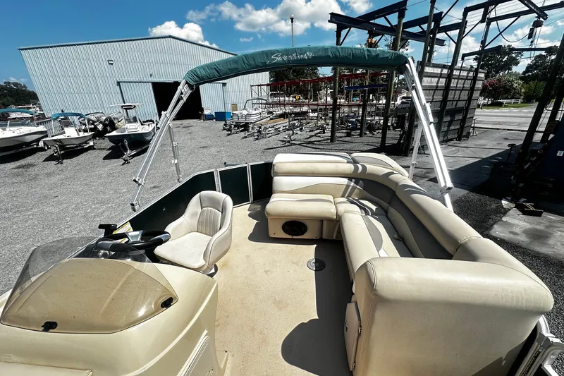 Slide: The Image of 2015 Godfrey 2286 Sweetwater Pontoon with beige seating, docked near a storage facility. - 4