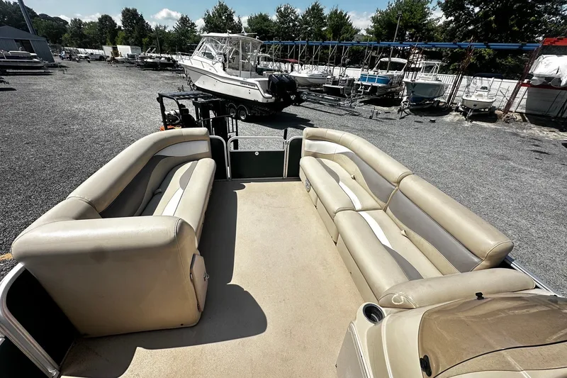 Slide: The Image of 2015 Godfrey 2286 Sweetwater Pontoon with beige seating, parked in a boatyard. - 8