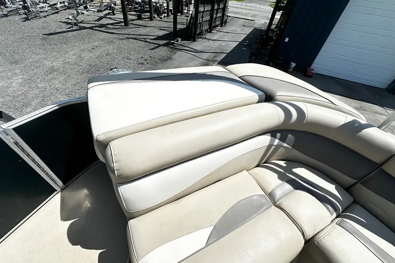 Slide: The Image of 2015 Godfrey 2286 Sweetwater Pontoon with beige seating, parked outdoors. - 10