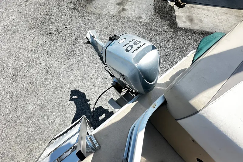 Slide: The Image of 2015 Godfrey 2286 Sweetwater Pontoon with Honda 90 outboard motor, parked on gravel. - 11