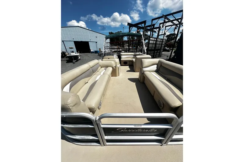 Slide: The Image of 2015 Godfrey 2286 Sweetwater Pontoon with beige seating, parked outdoors under a blue sky. - 5